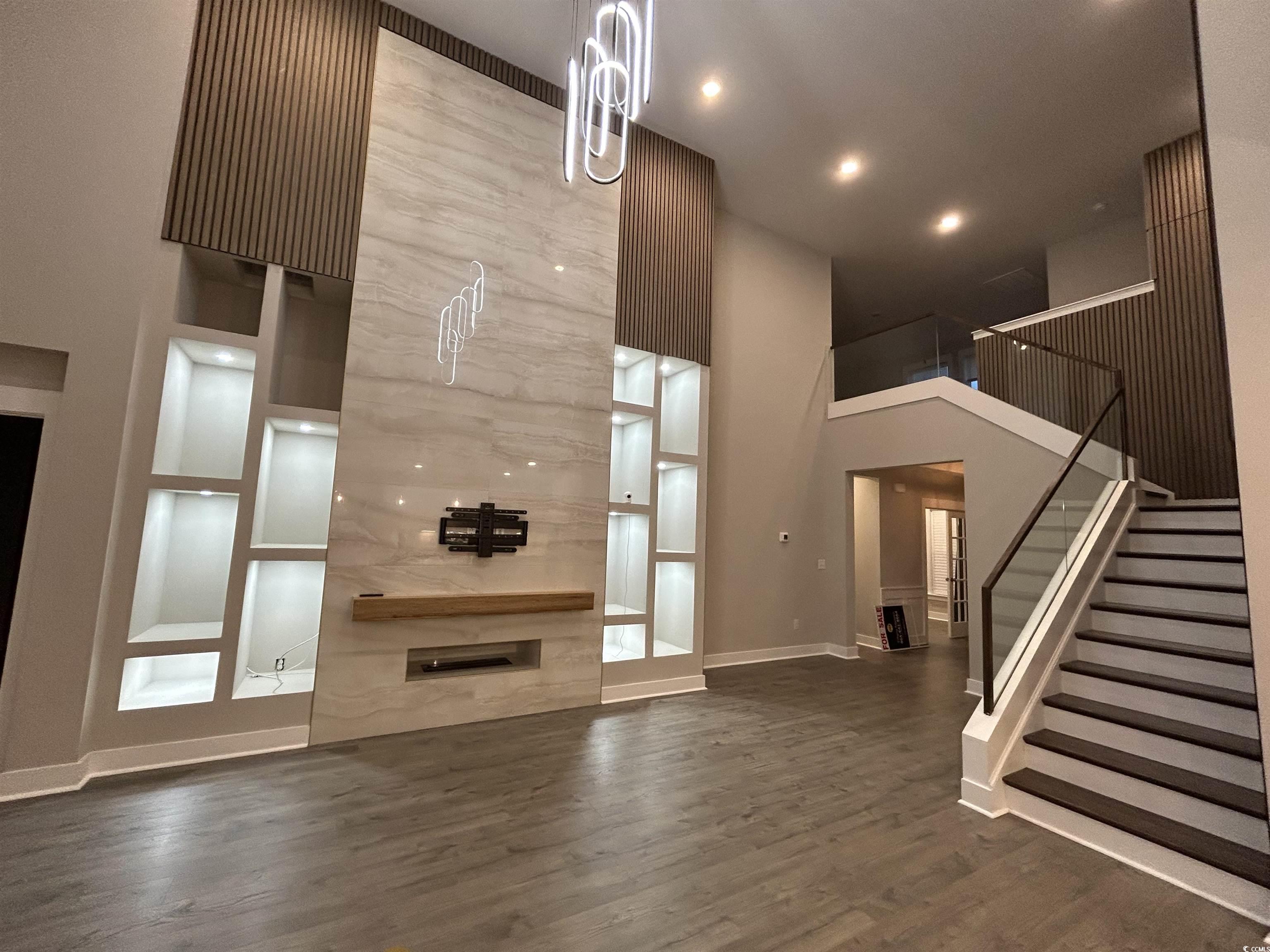 2108 Ballast Court Myrtle Beach, SC 29579 - Photo 3 of 37 Unfurnished living room featuring dark wood-type flooring, stairs, a towering ceiling, recessed lighting, and a large fireplace