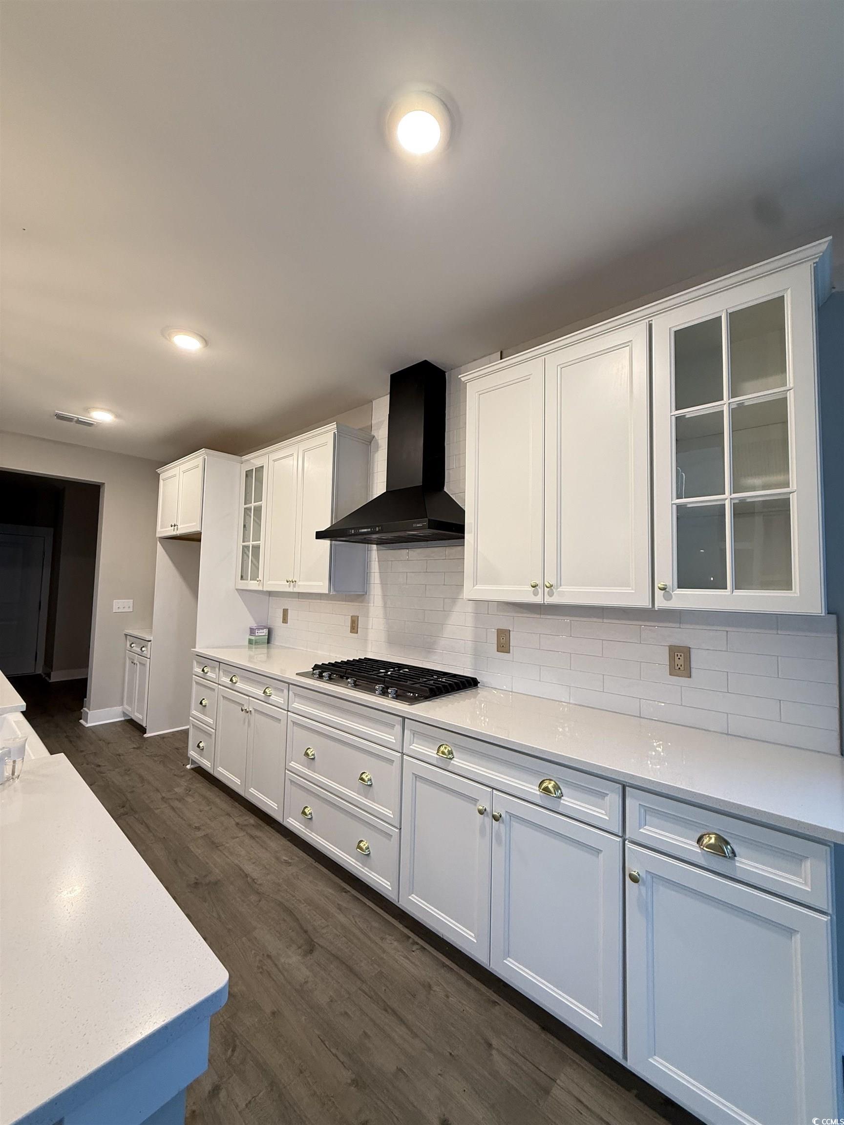 2108 Ballast Court Myrtle Beach, SC 29579 - Photo 8 of 37 Kitchen featuring glass insert cabinets, wall chimney range hood, white cabinets, decorative backsplash, and dark wood finished floors