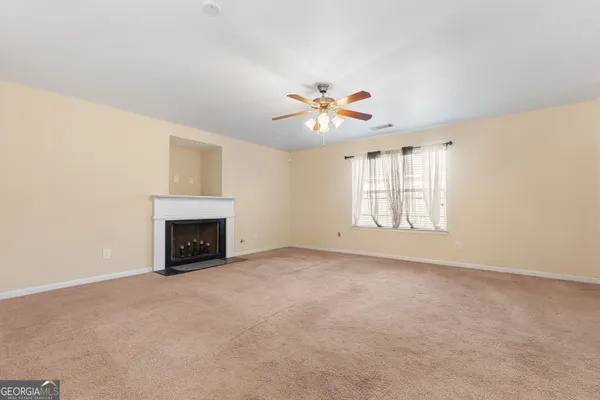 an empty room with chandelier fan and windows