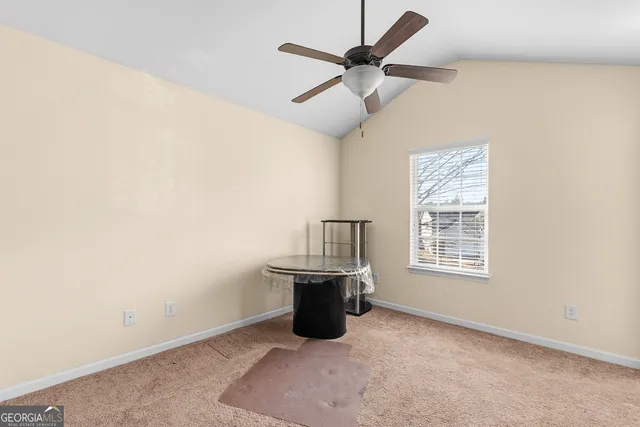 an empty room with ceiling fan and windows
