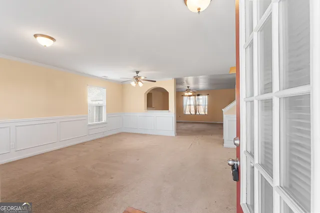 a view of a big room with windows and chandelier fan