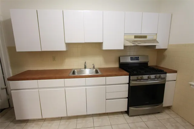 a kitchen with stainless steel appliances granite countertop a stove a sink and a white cabinets