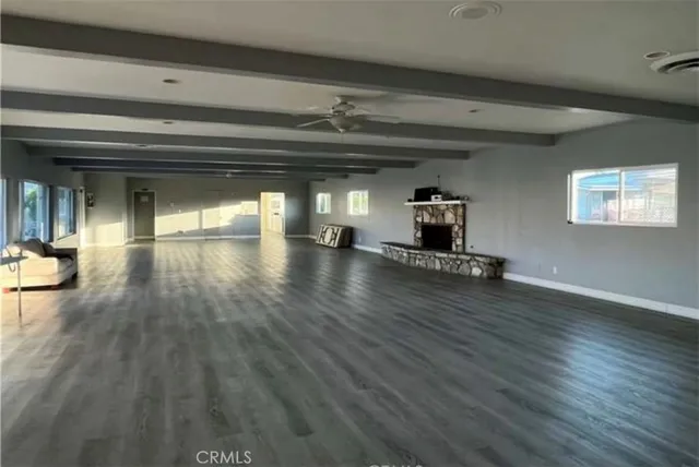 an empty room with wooden floor a fireplace and windows