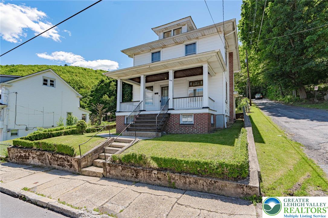 159 West Ridge Street Nesquehoning, PA 18240 - Photo 3 of 55 A classic facade with a covered porch invites residents into this charming home, set against a backdrop of natural greenery.