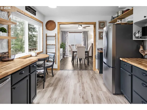 a open kitchen with stainless steel appliances granite countertop a refrigerator a stove a sink a dining table and chairs with wooden floor