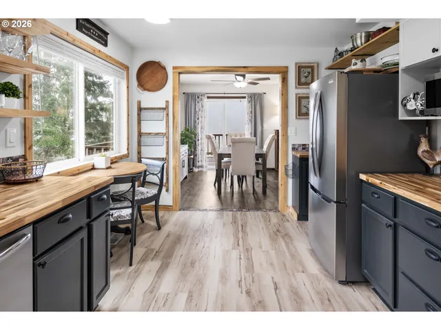 a open kitchen with stainless steel appliances granite countertop a refrigerator a stove a sink a dining table and chairs with wooden floor