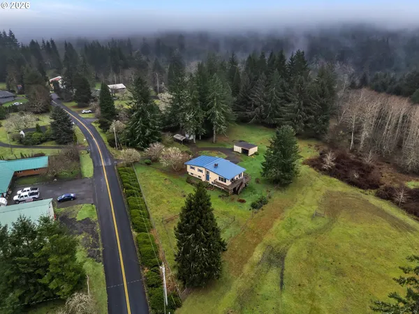 an aerial view of a residential houses with outdoor space and trees