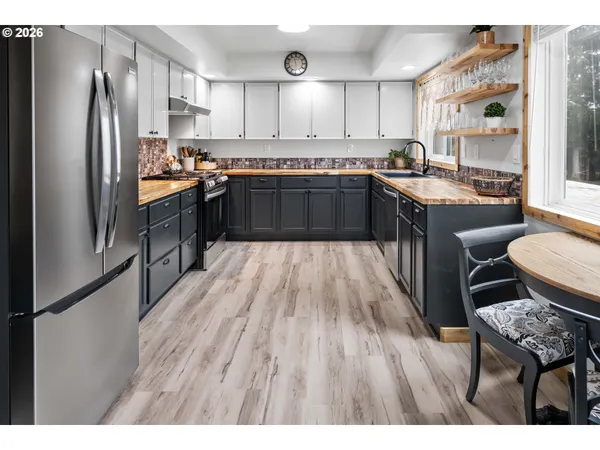 a kitchen with stainless steel appliances granite countertop a refrigerator a sink dishwasher a stove with wooden cabinets and floor