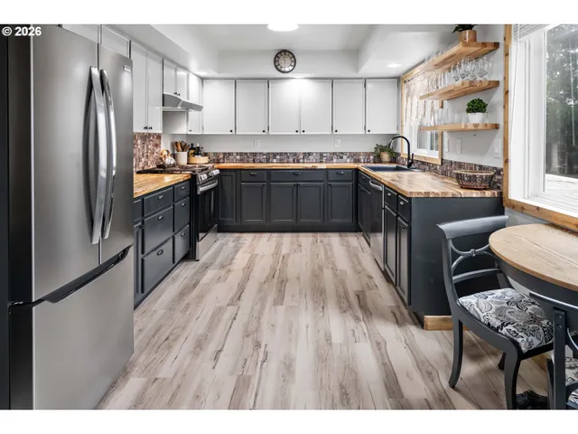 a kitchen with stainless steel appliances granite countertop a refrigerator a sink dishwasher a stove with wooden cabinets and floor