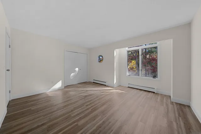 a view of an empty room with window and wooden floor