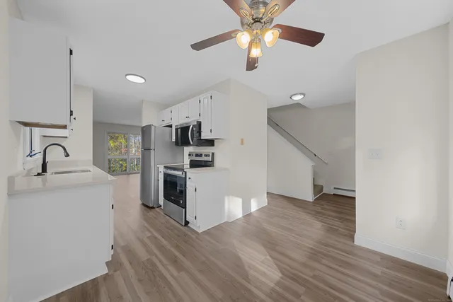 a view of a kitchen with a sink a ceiling fan and wooden floor