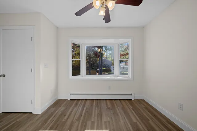 a view of an empty room with wooden floor and a window