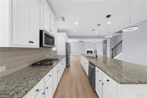a large kitchen with stainless steel appliances granite countertop a lot of counter space and wooden floors