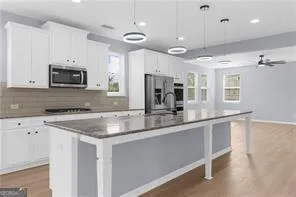 a kitchen with stainless steel appliances granite countertop a sink a stove a microwave a center island and cabinets