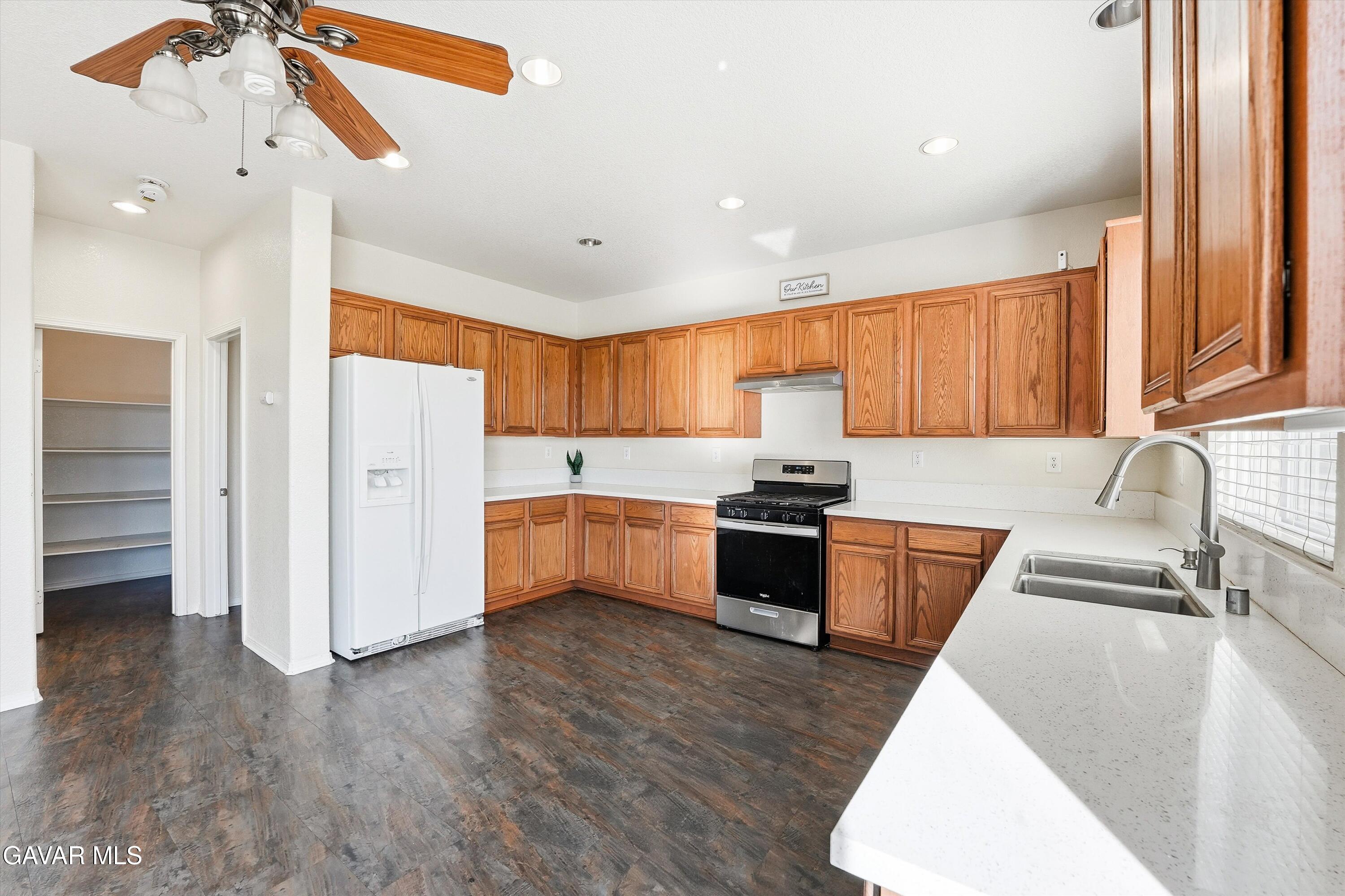 44232 Begonia Street Lancaster, CA 93535 - Photo 11 of 39 a large kitchen with stainless steel appliances granite countertop a refrigerator a sink dishwasher a stove with wooden floor and cabinets