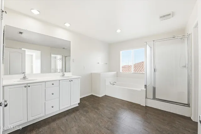 a spacious bathroom with a double vanity sink a mirror and a shower