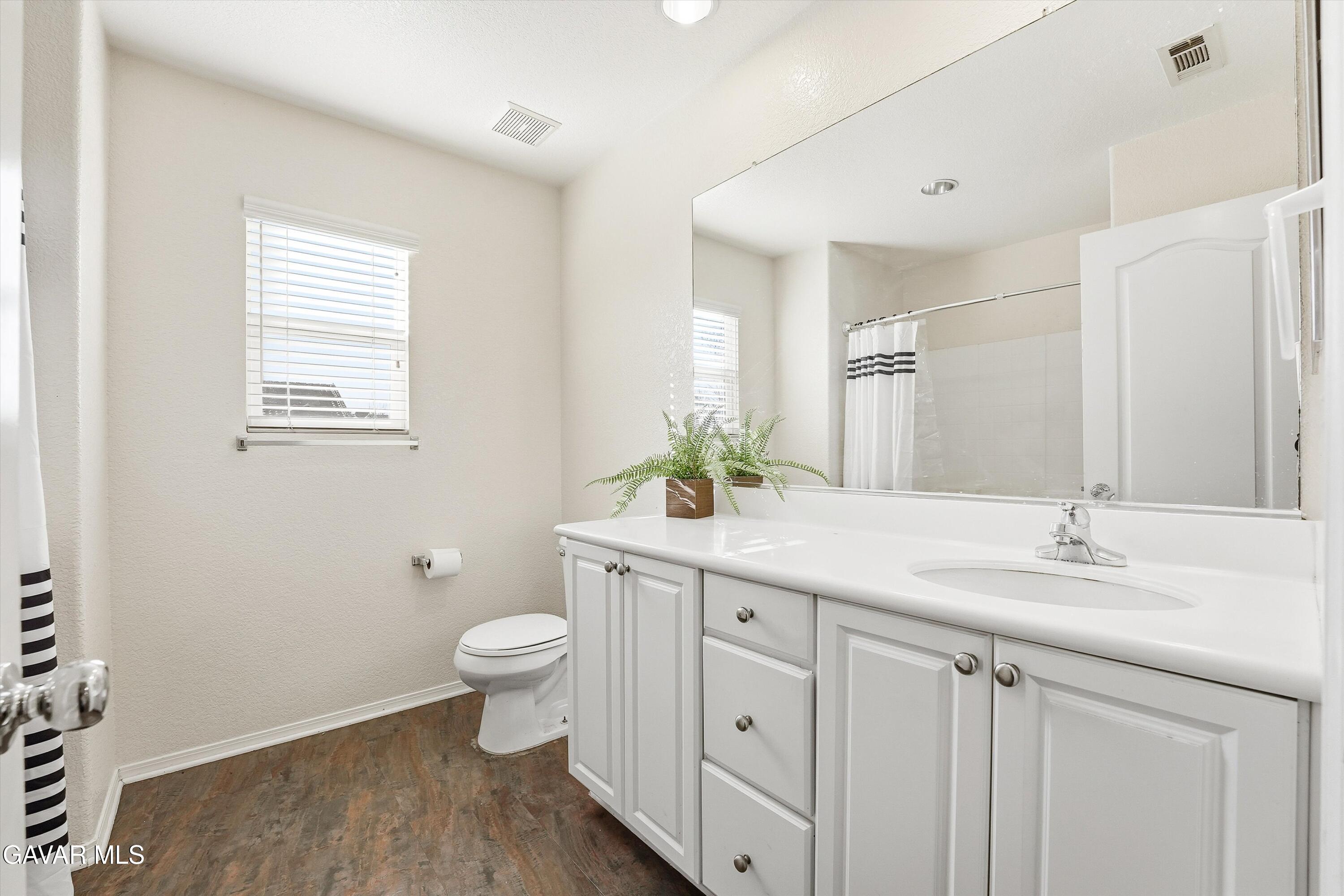 44232 Begonia Street Lancaster, CA 93535 - Photo 34 of 39 a bathroom with a granite countertop sink a toilet and a mirror