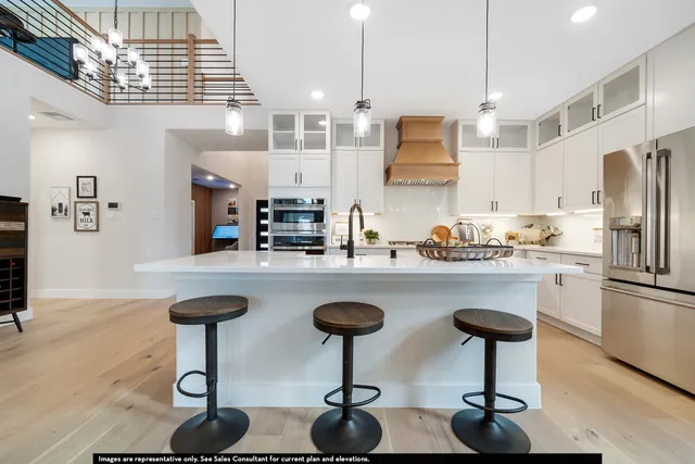 a kitchen with stainless steel appliances granite countertop a sink a stove a refrigerator and chairs