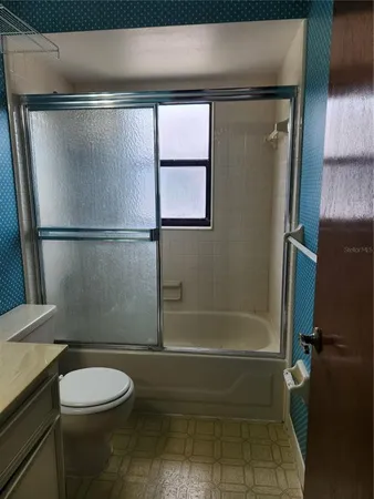 a bathroom with a granite countertop bathtub shower sink vanity and toilet