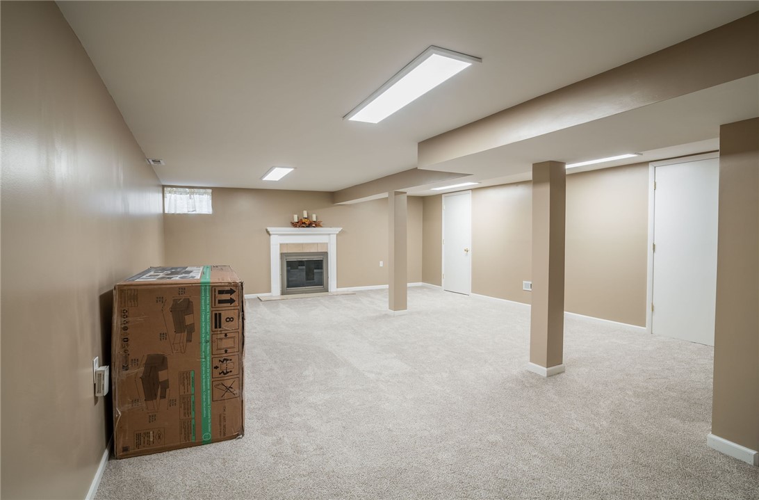 1463 Chelsea Road Troy, OH 45373 - Photo 29 of 39 This spacious basement offers a cozy fireplace and neutral carpeting, creating a versatile living space.