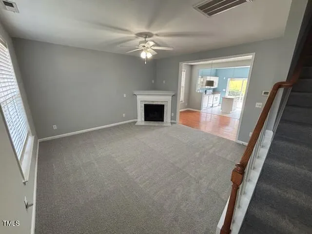 an empty room with windows fireplace and chandelier