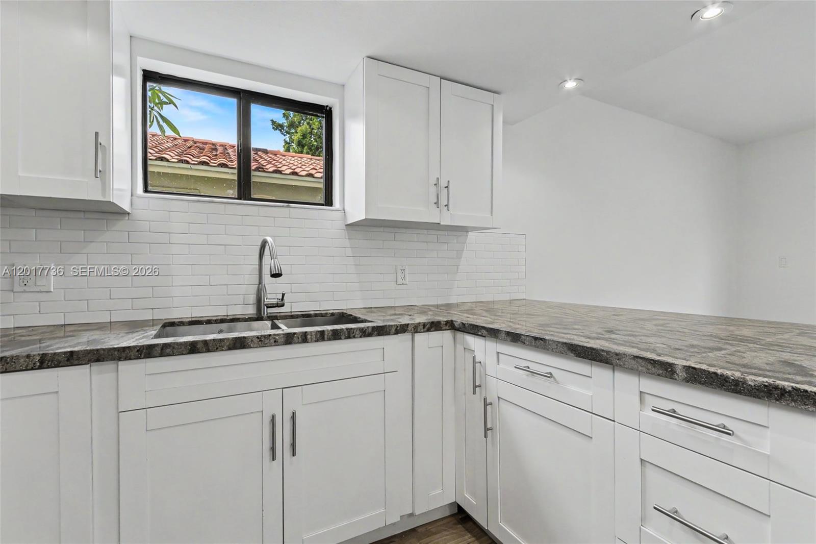 122 Southwest 56th Avenue Miami, FL 33144 - Photo 12 of 48 a kitchen with granite countertop white cabinets and white appliances