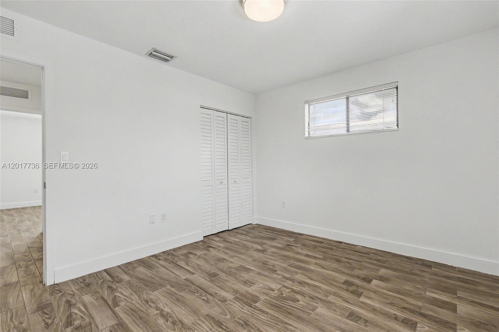 122 Southwest 56th Avenue Miami, FL 33144 - Photo 25 of 48 an empty room with wooden floor and windows