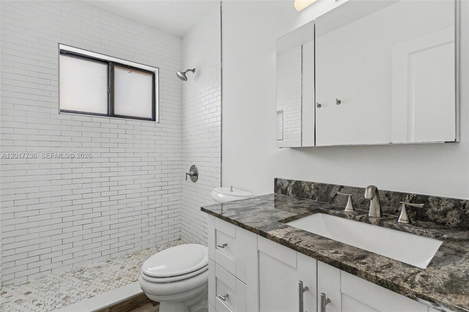 122 Southwest 56th Avenue Miami, FL 33144 - Photo 30 of 48 a bathroom with a granite countertop sink a toilet and mirror