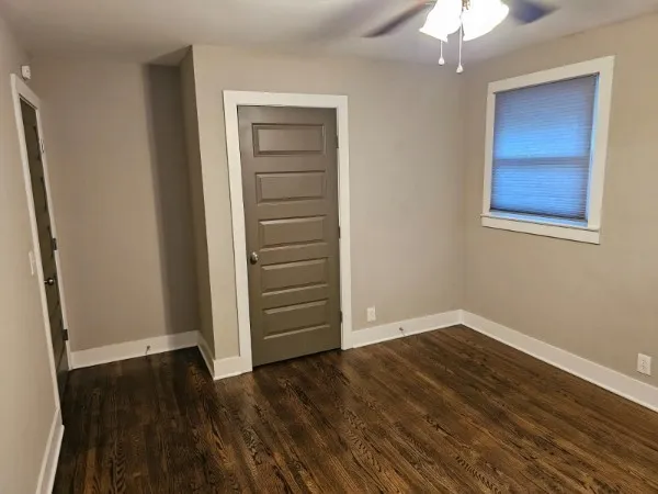 an empty room with wooden floor closet and windows