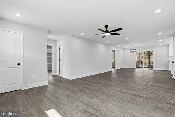an empty room with wooden floor and a ceiling fan