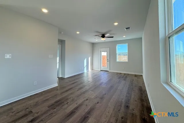 an empty room with wooden floor and windows