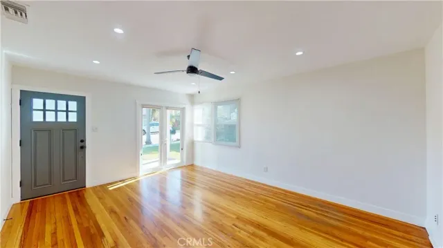 a view of an empty room with wooden floor and windows