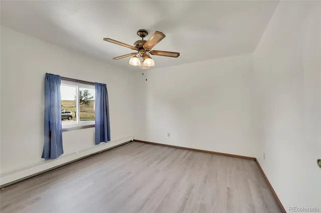 an empty room with wooden floor fan and windows