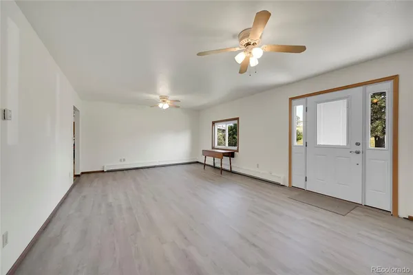 an empty room with wooden floor chandelier and windows