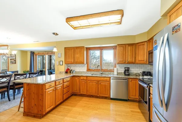 a kitchen with granite countertop wooden floors stainless steel appliances a sink and a window