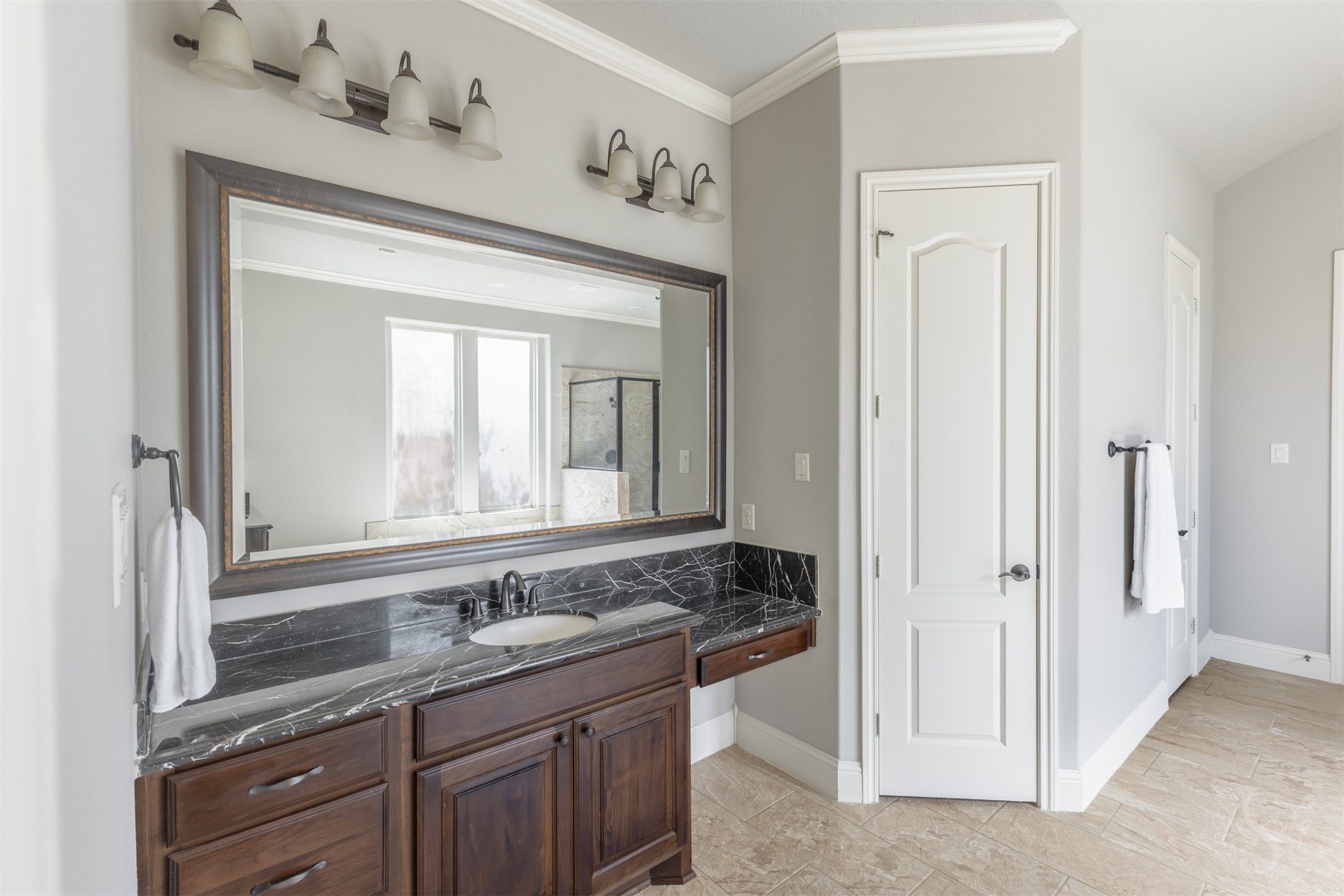 5803 Mustang Ridge Lane Fulshear, TX 77441 - Photo 17 of 48 Secondary vanity in the spacious primary bath features rich cabinetry, granite countertops and an oversized framed mirror with updated lighting. Thoughtfully designed with abundant storage and generous counter space, the layout offers both comfort and convenience.