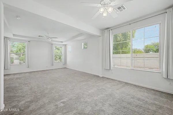 an empty room with windows and chandelier fan