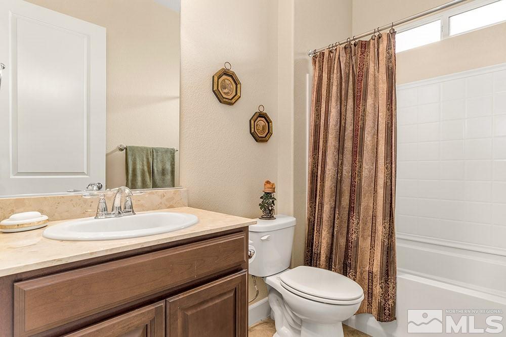 9266 Maplehurst Trail Reno, NV 89523 - Photo 27 of 29 a bathroom with a sink a toilet a mirror and shower curtain
