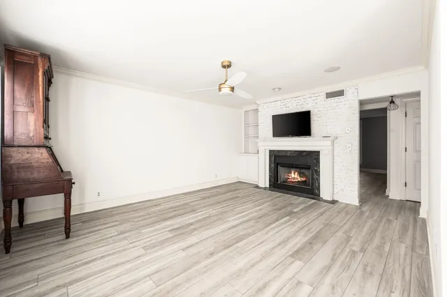 a view of an empty room with wooden floor fireplace and a window