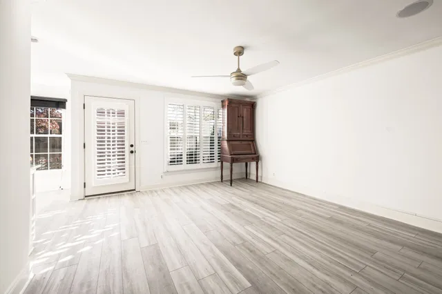 a view of an empty room with a window and wooden floor