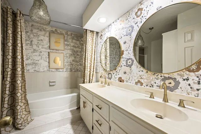 a bathroom with a double vanity sink mirror and bathtub