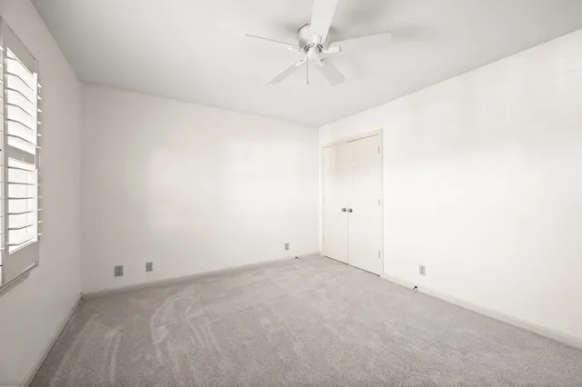 an empty room with a window and a fan