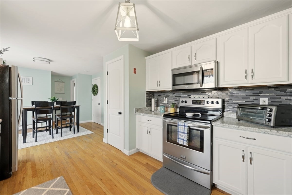 19 Station Street Wareham, MA 02571 - Photo 17 of 41 a kitchen with stainless steel appliances granite countertop a stove a refrigerator a sink a dining table and chairs with wooden floor