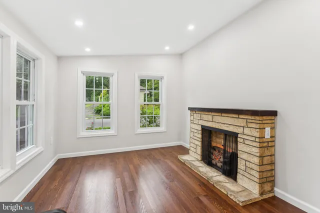 an empty room with windows and fireplace