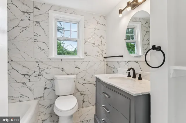 a bathroom with a granite countertop toilet sink and mirror