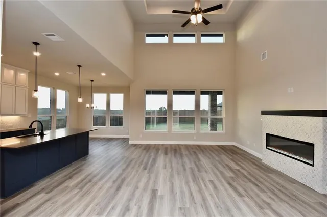 a view of an empty room with wooden floor and a kitchen