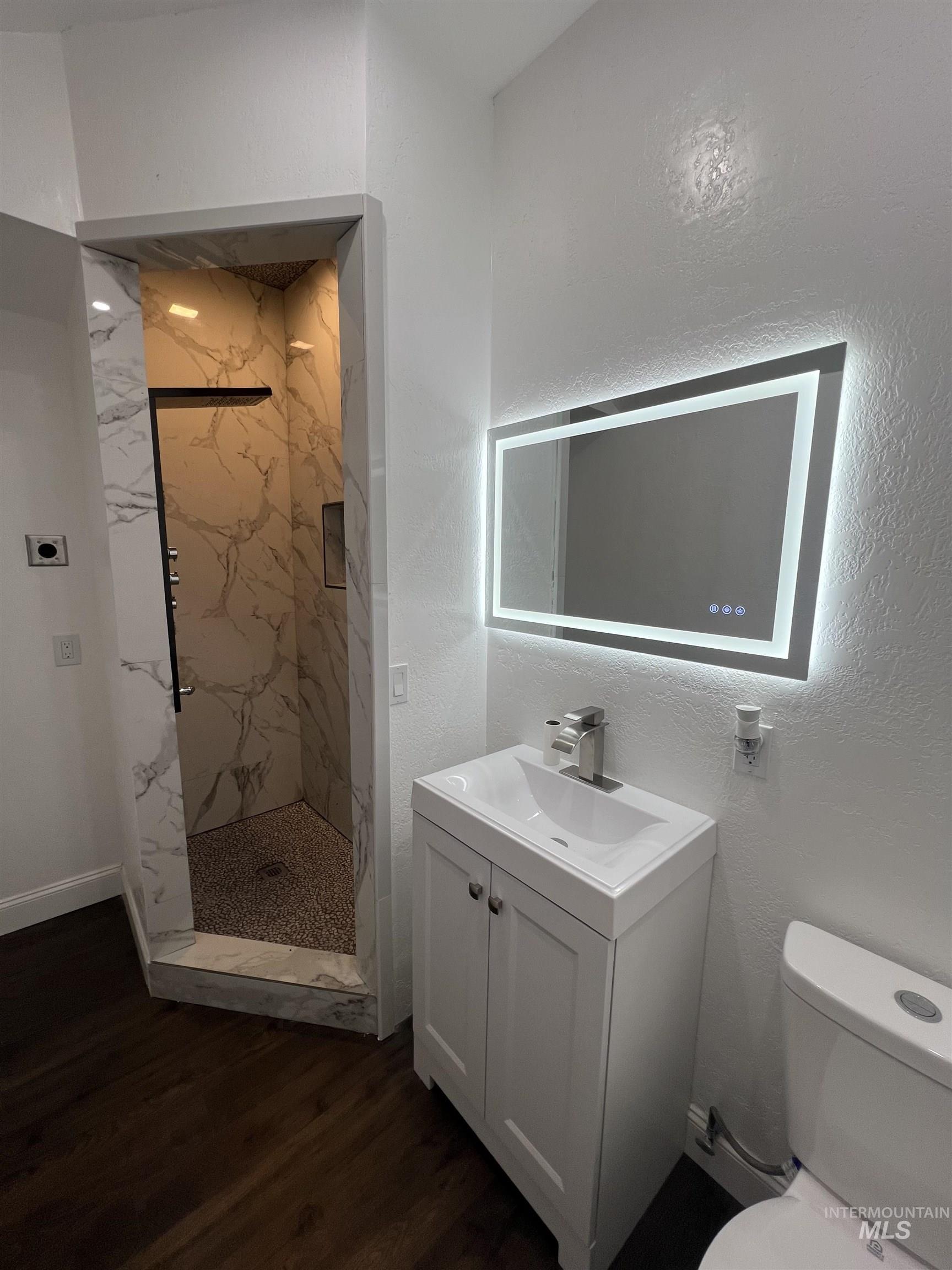 511 North 10th Street Payette, ID 83661 - Photo 12 of 18 Full bathroom featuring a marble finish shower, vanity, a textured wall, and dark wood-type flooring