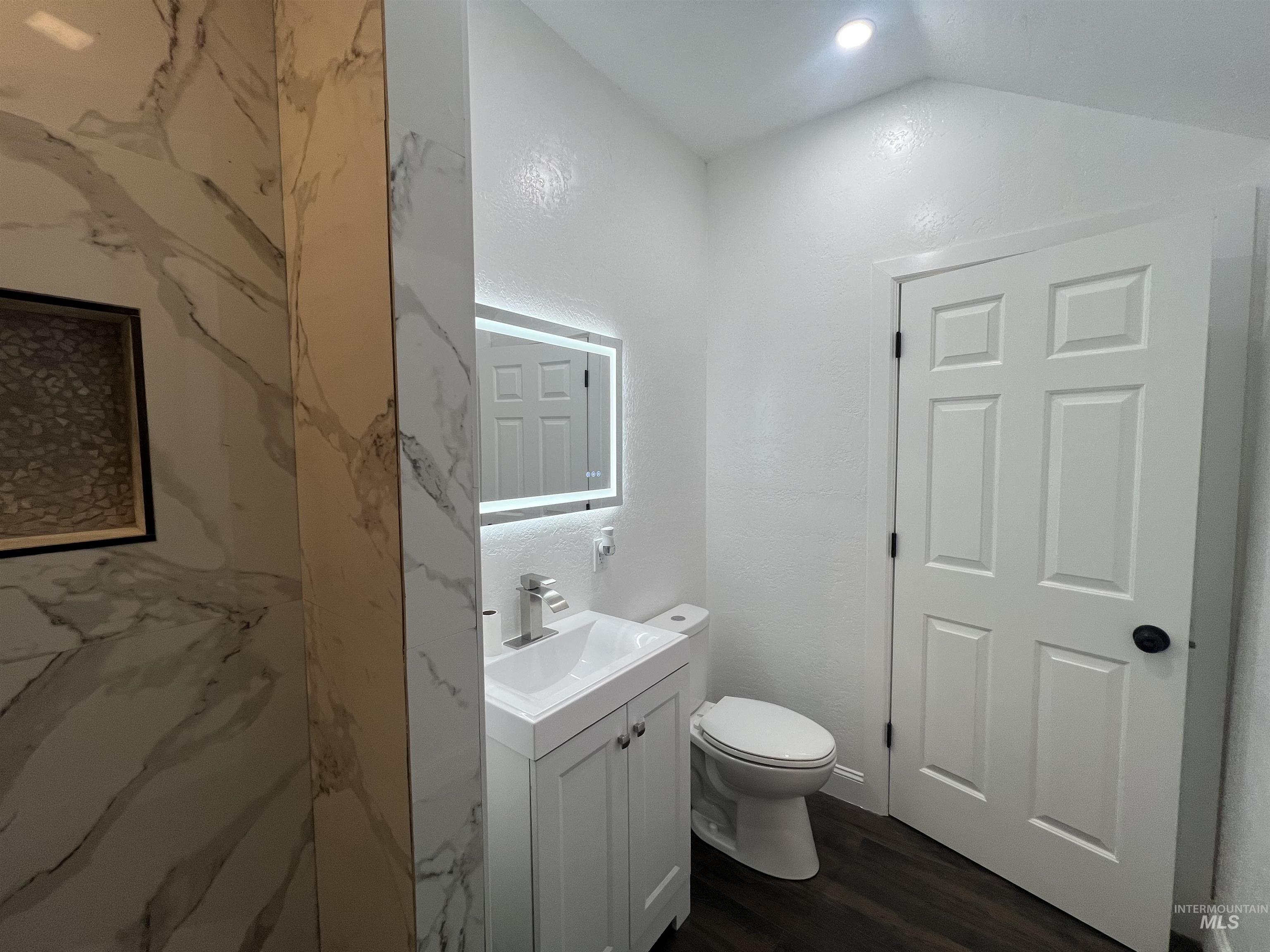 511 North 10th Street Payette, ID 83661 - Photo 13 of 18 Half bath with vanity, dark wood-style flooring, and vaulted ceiling