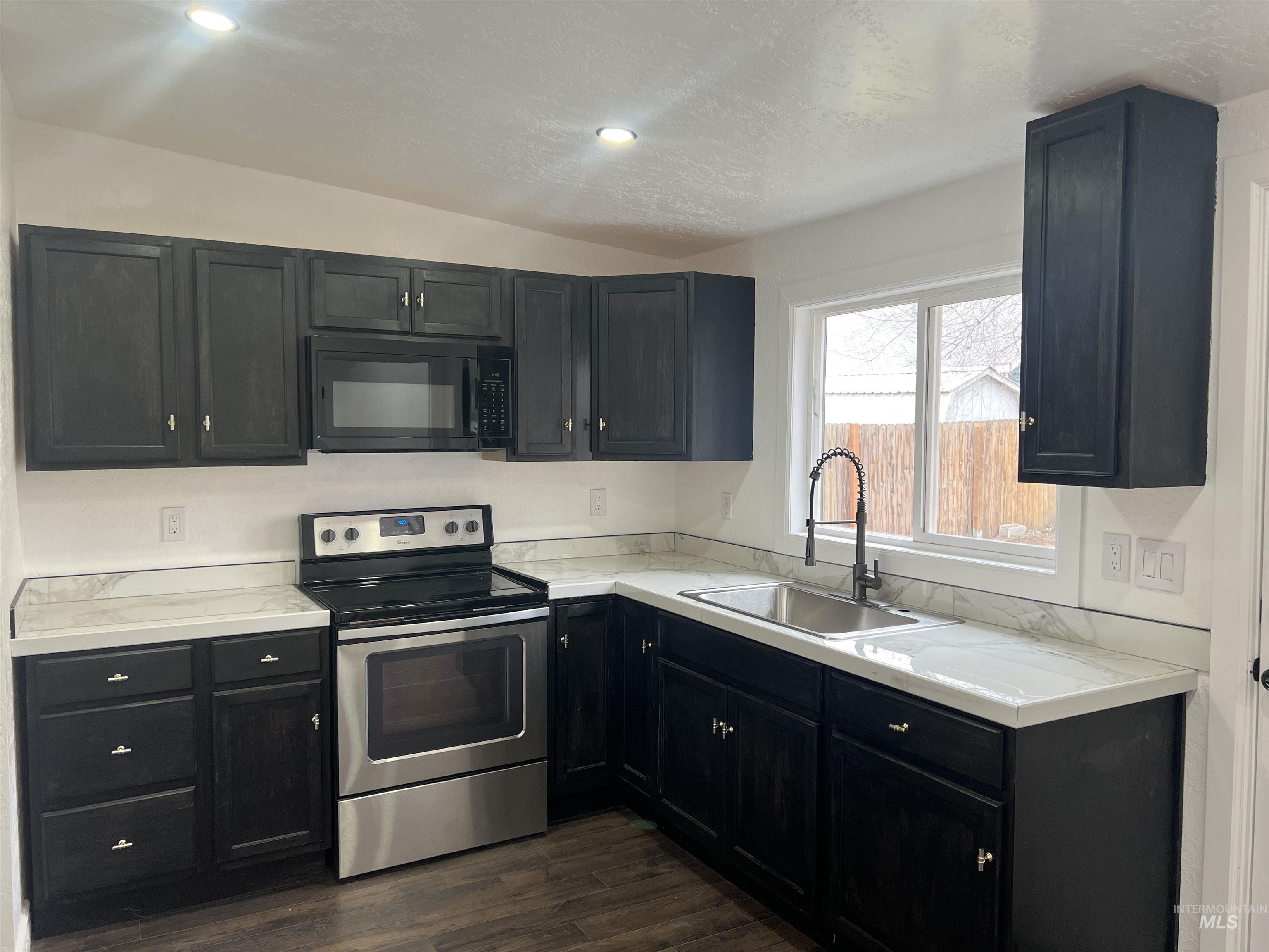 511 North 10th Street Payette, ID 83661 - Photo 3 of 18 Kitchen with electric range, light countertops, dark cabinets, recessed lighting, and a textured ceiling