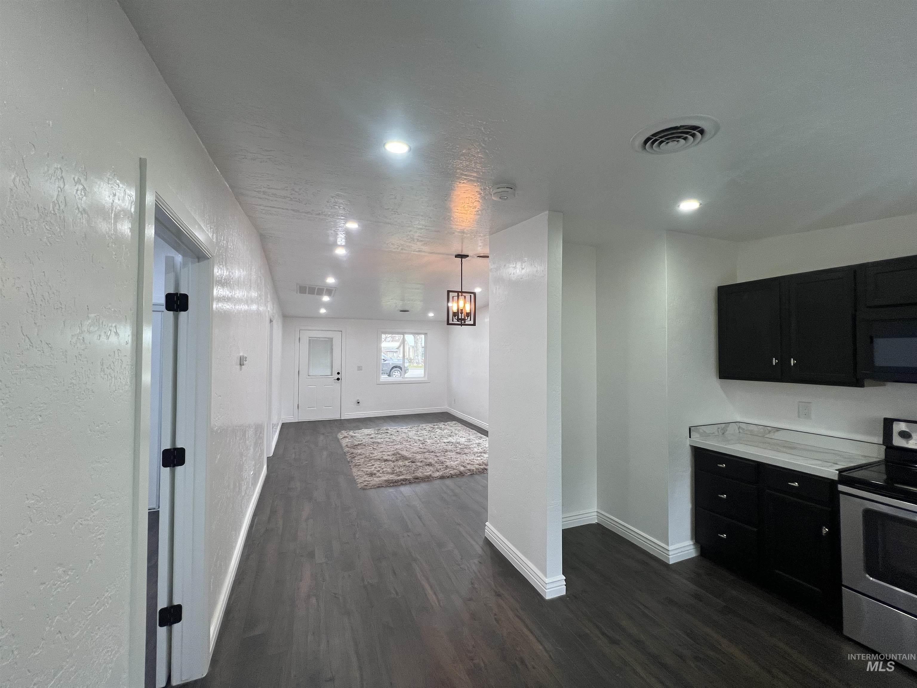 511 North 10th Street Payette, ID 83661 - Photo 7 of 18 Kitchen featuring light countertops, dark cabinetry, stainless steel electric stove, dark wood-type flooring, and a textured wall